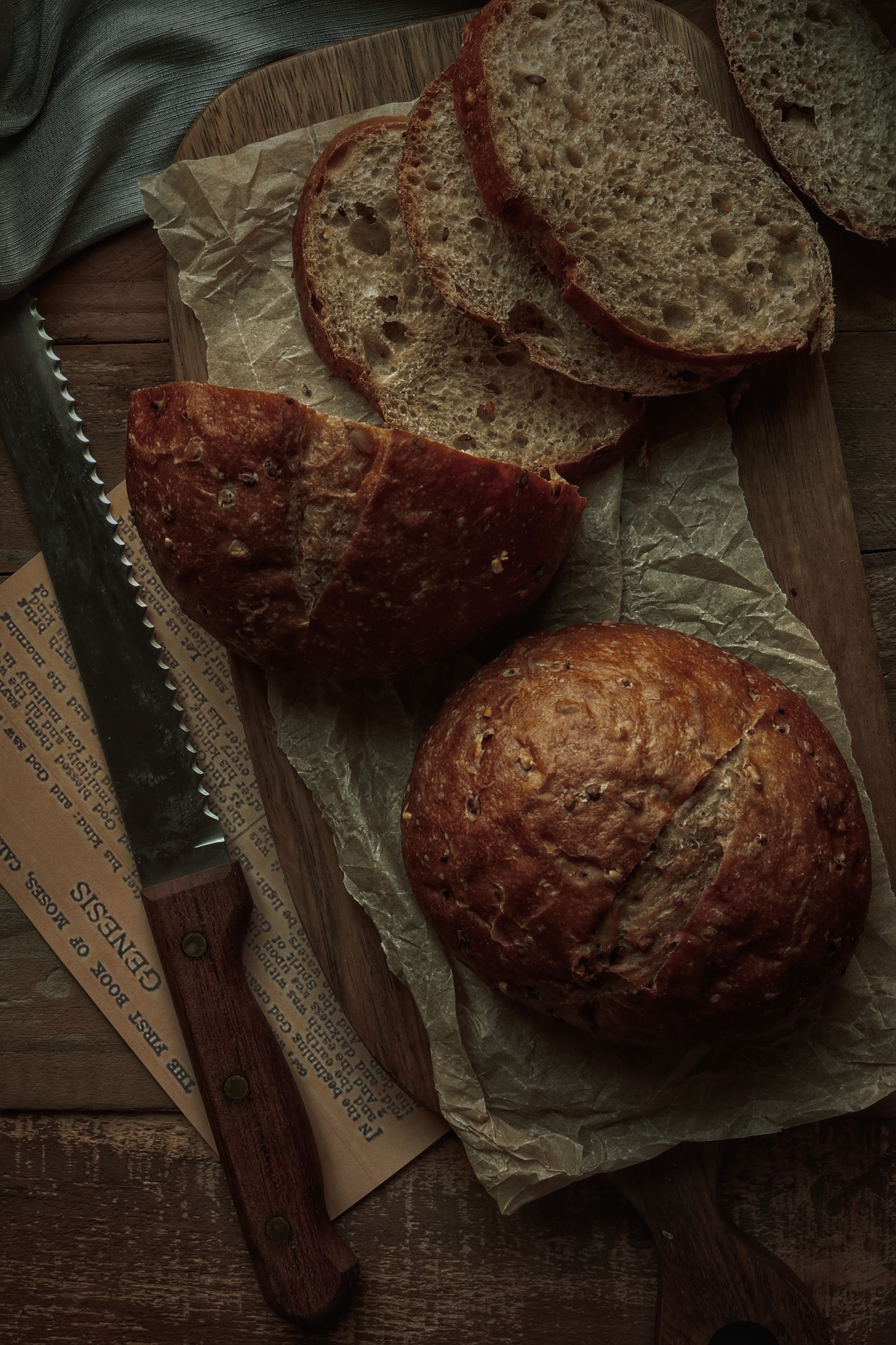 Top view of freshly baked artisan bread on a wooden board with a bread knife